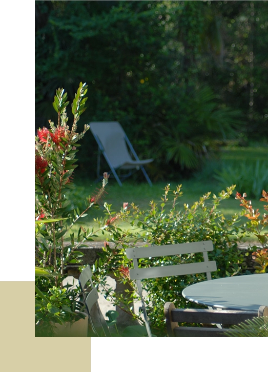 Chaise longue dans un jardin verdoyant, entouré de fleurs et d’arbustes.